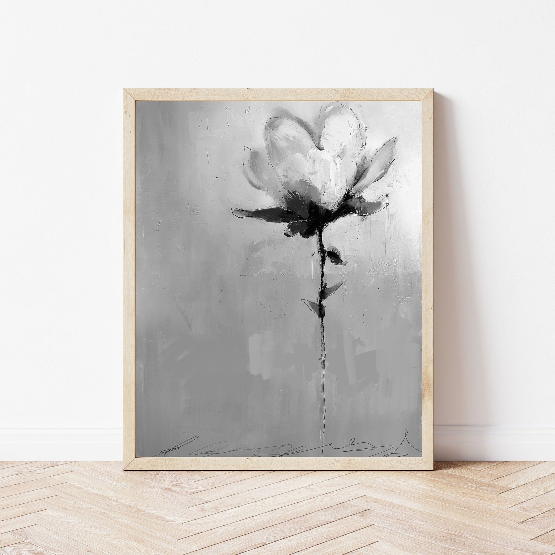 A framed grayscale abstract painting of a single flower. The flower is rendered in shades of gray and black, with visible brushstrokes. The background is a textured gray canvas. The painting has a minimalist aesthetic and evokes a sense of serenity. The frame is light wood. The artwork is suitable for modern or contemporary home decor.